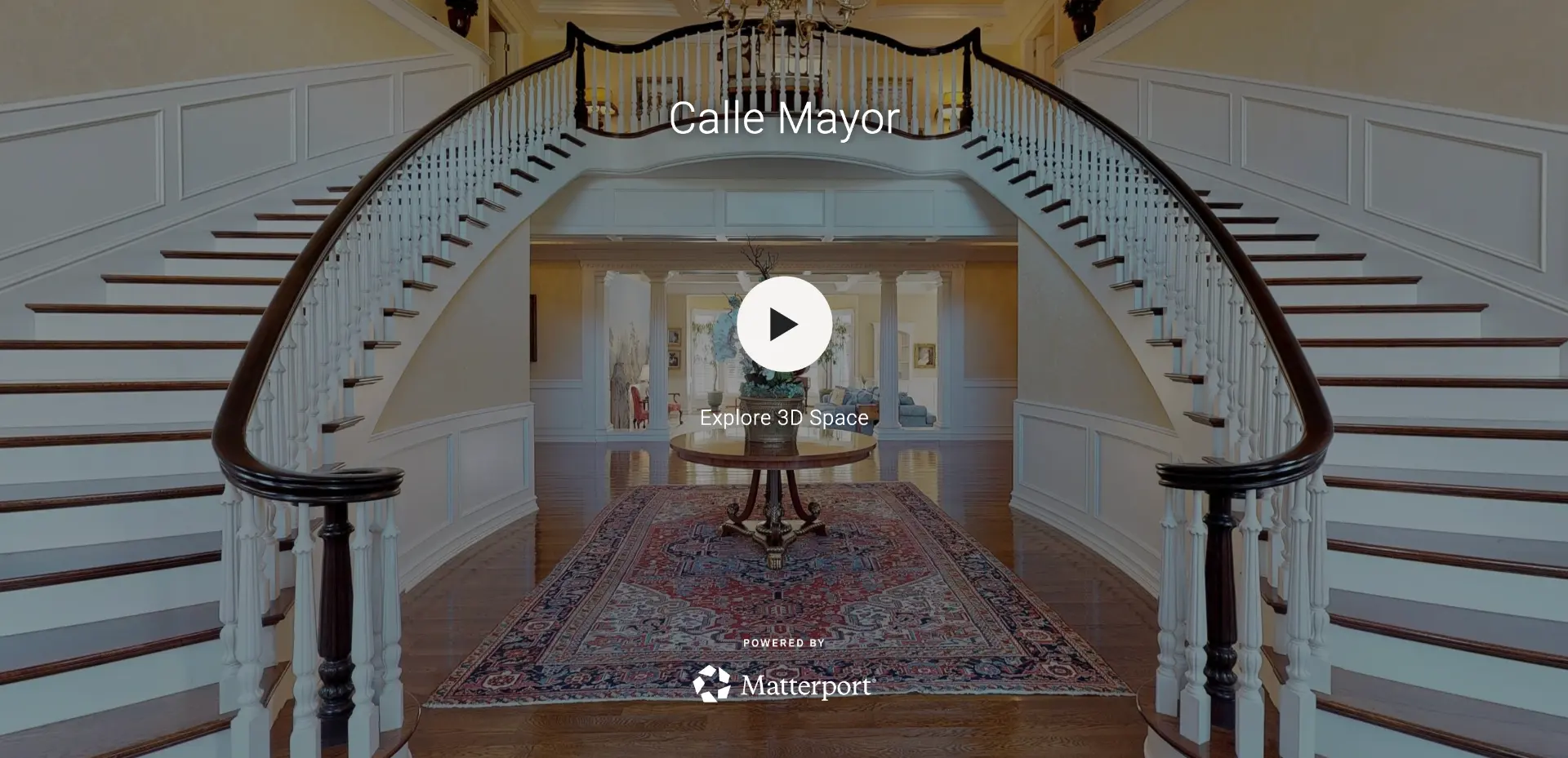 Matterport 3D tour of a foyer with a curved double staircase, hardwood floors and an oriental rug