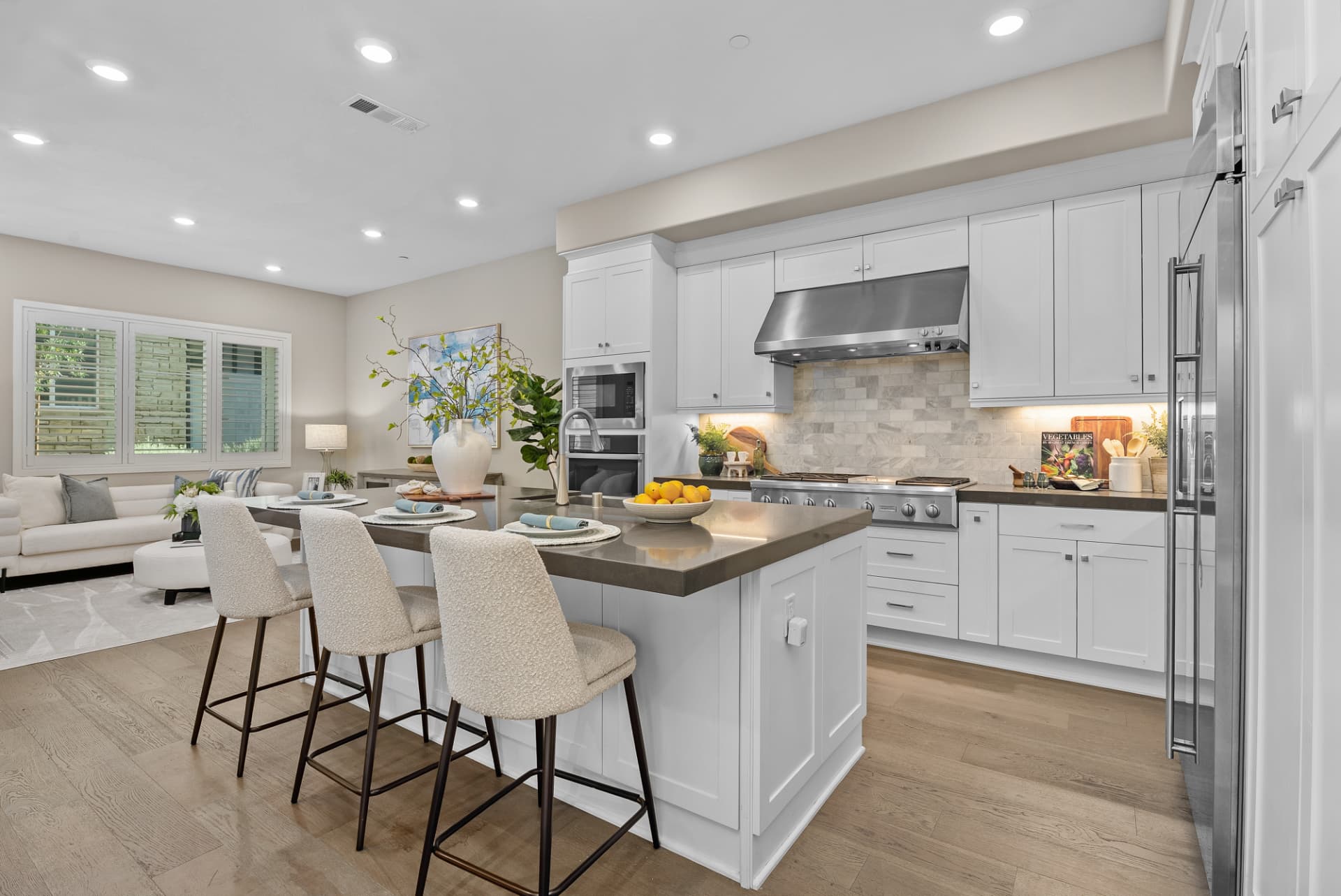 Zillow 3D tour of a bright kitchen with a large island, barstools and an adjoining living room