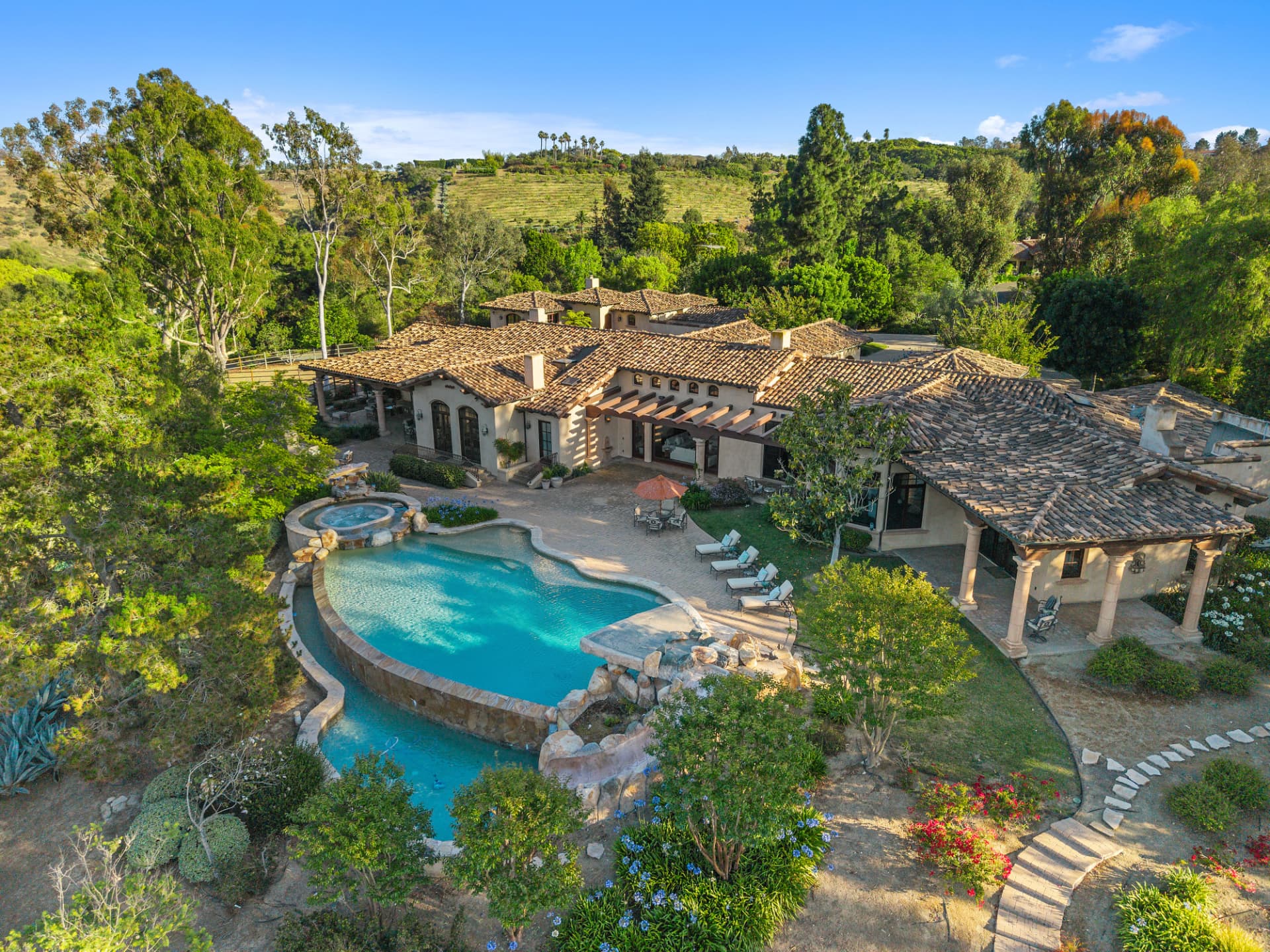 Aerial view of a Spanish-style estate with a free-form pool and gardens