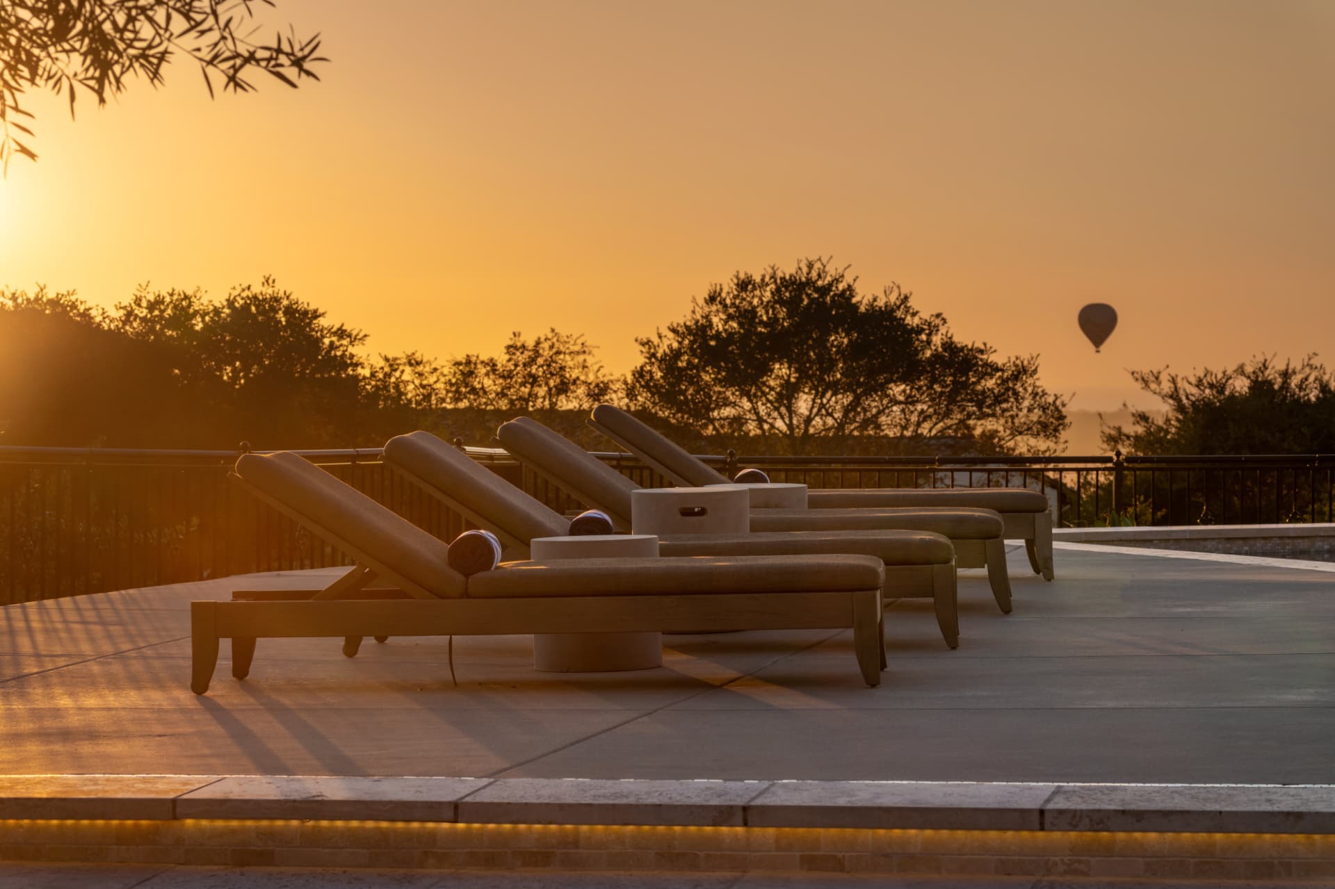 Sunset terrace with lounge chairs and a hot-air balloon on the horizon